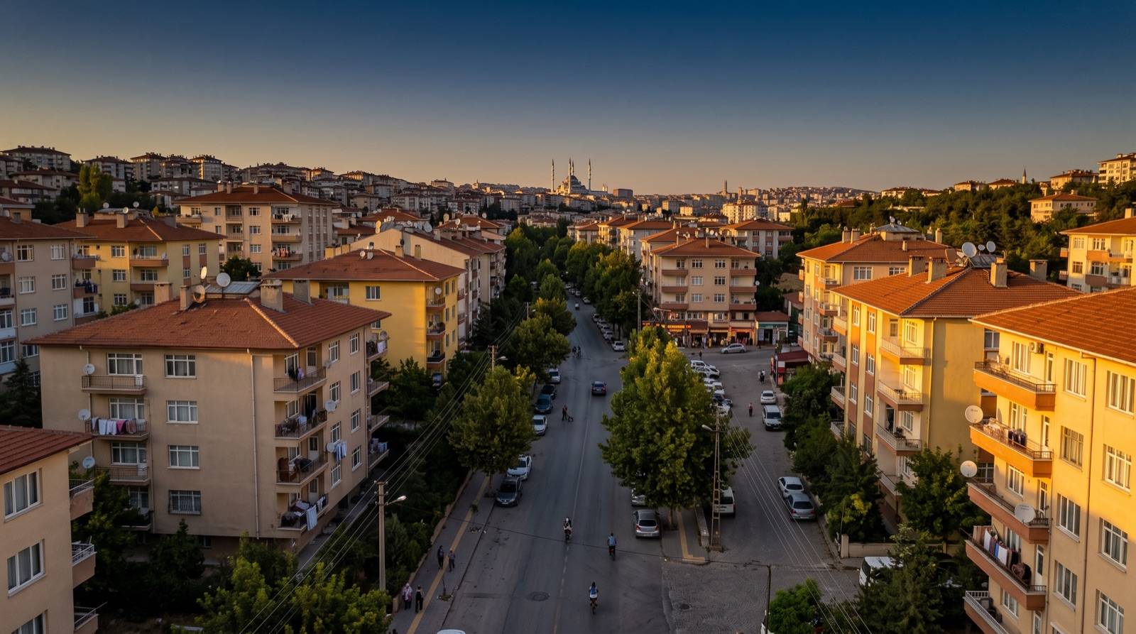 Aydın Efeler mahalleleri rehberi için temsili görsel: gün batımında ağaçlı bir cadde boyunca uzanan kiremit çatılı apartmanlar